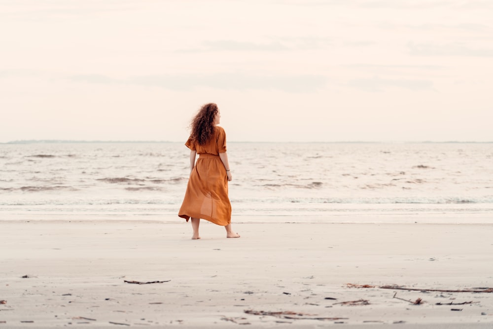 a woman standing on a beach next to the ocean