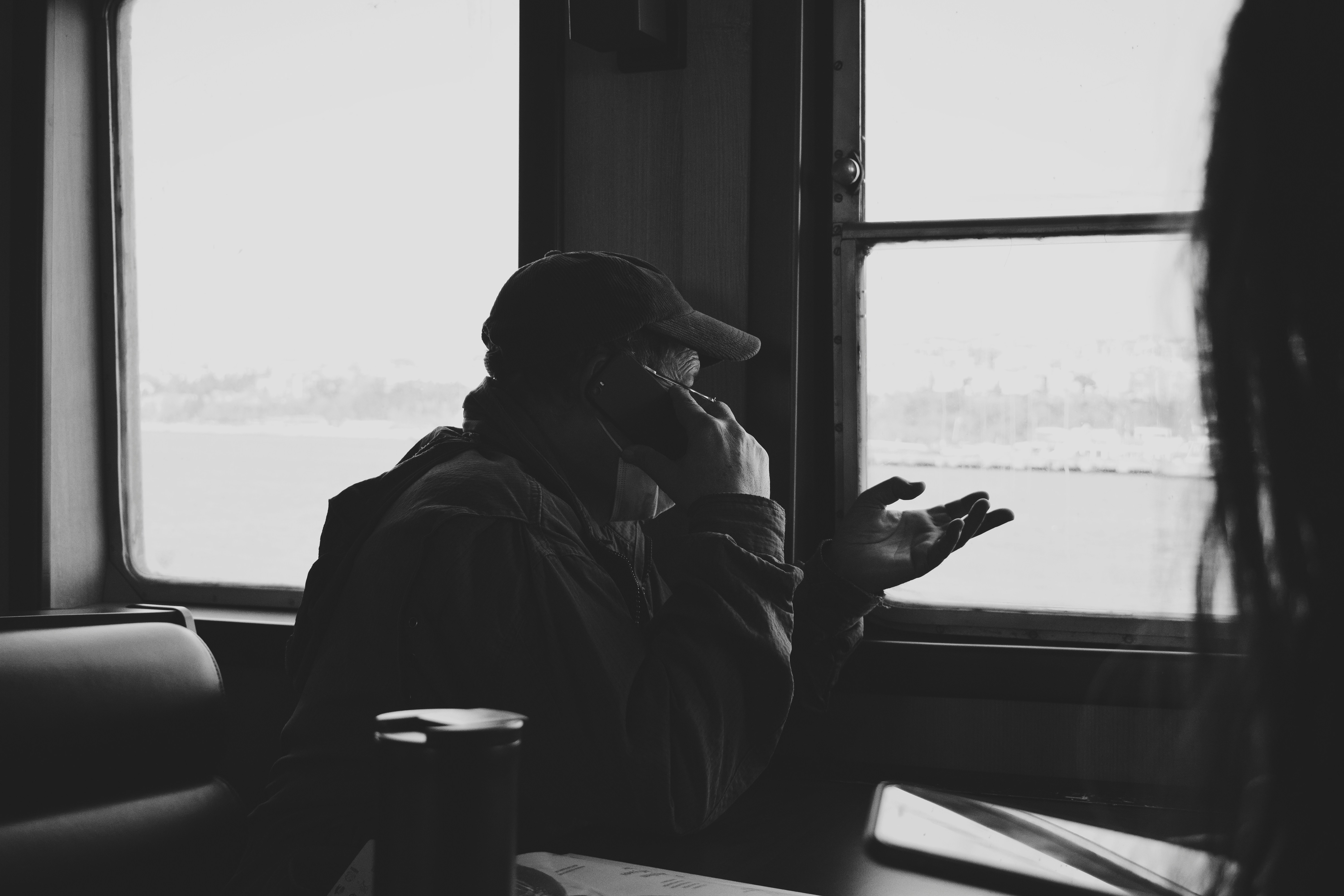 man in black jacket sitting by the window