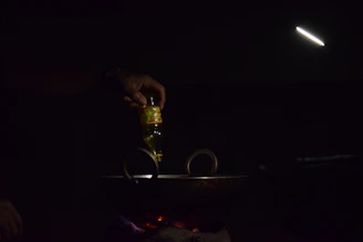 A hand pouring rich mustard oil into a traditional cooking pan, capturing the warm golden hue.