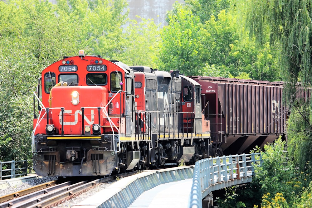 Treno rosso e nero sui binari ferroviari durante il giorno