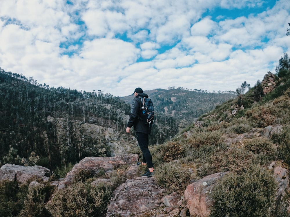 man in black jacket standing on rock during daytime