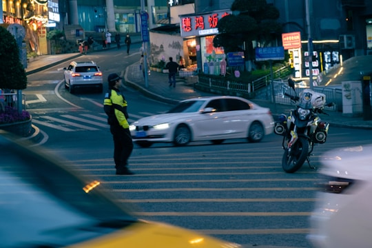 A determined police officer standing guard in a vibrant city street at dusk.