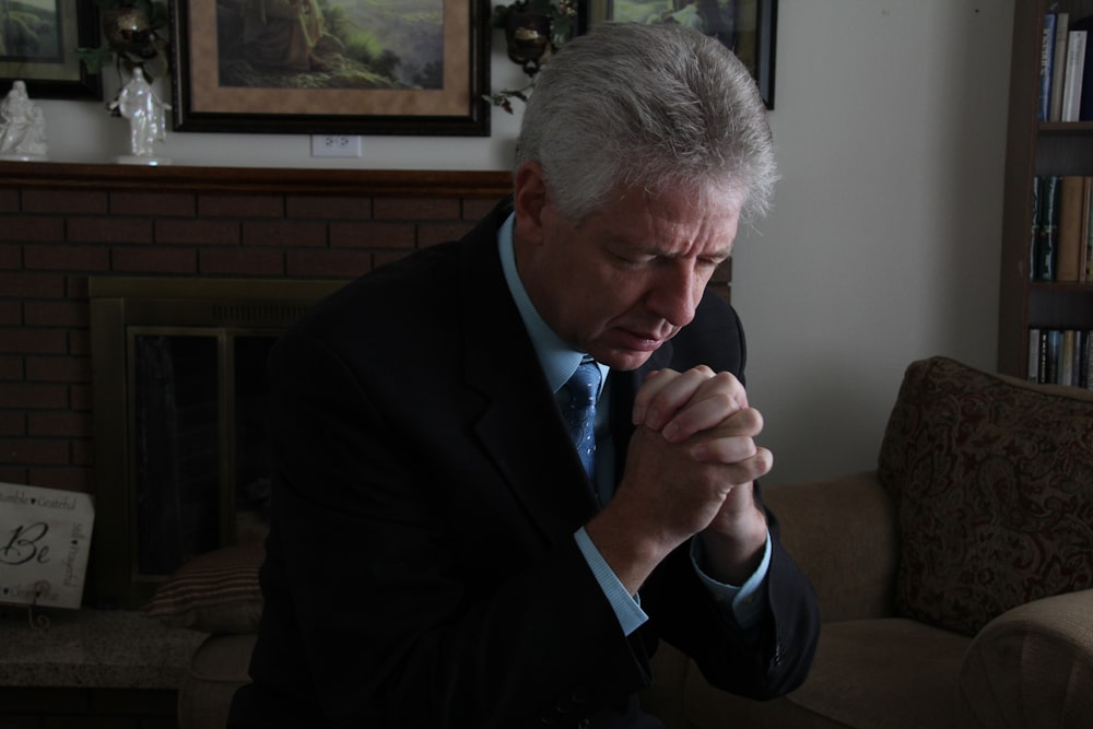 man in black suit jacket sitting on brown sofa