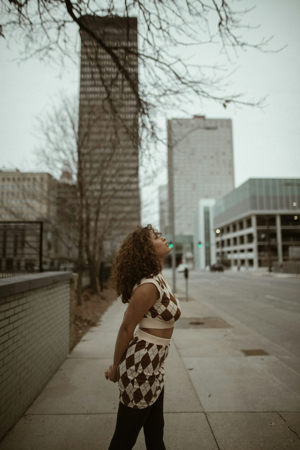 woman in black and white polka dot dress standing on sidewalk during daytime