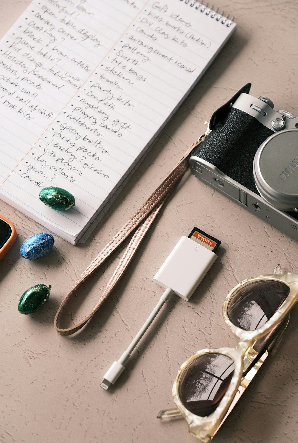 black and silver camera beside white printer paper and brown wooden chopsticks