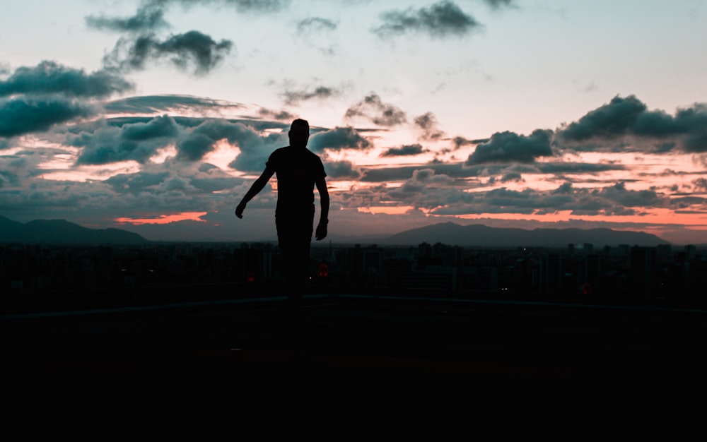 silhouette of man standing on the field during sunset