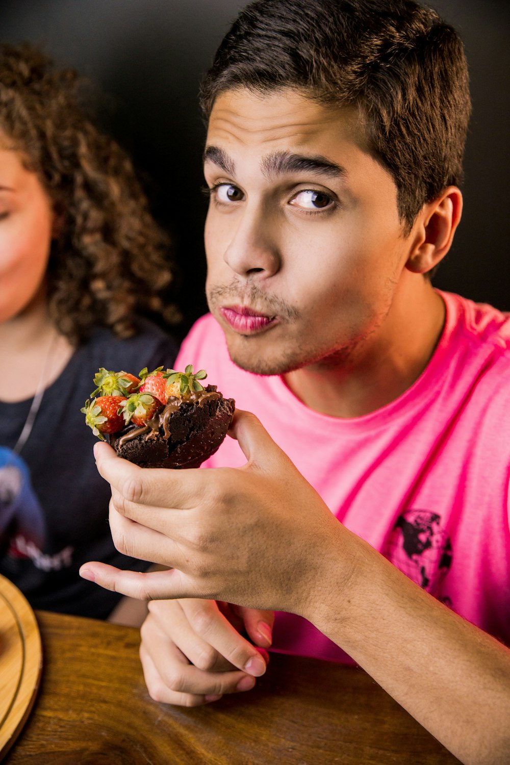 boy in pink crew neck t-shirt holding chocolate cake