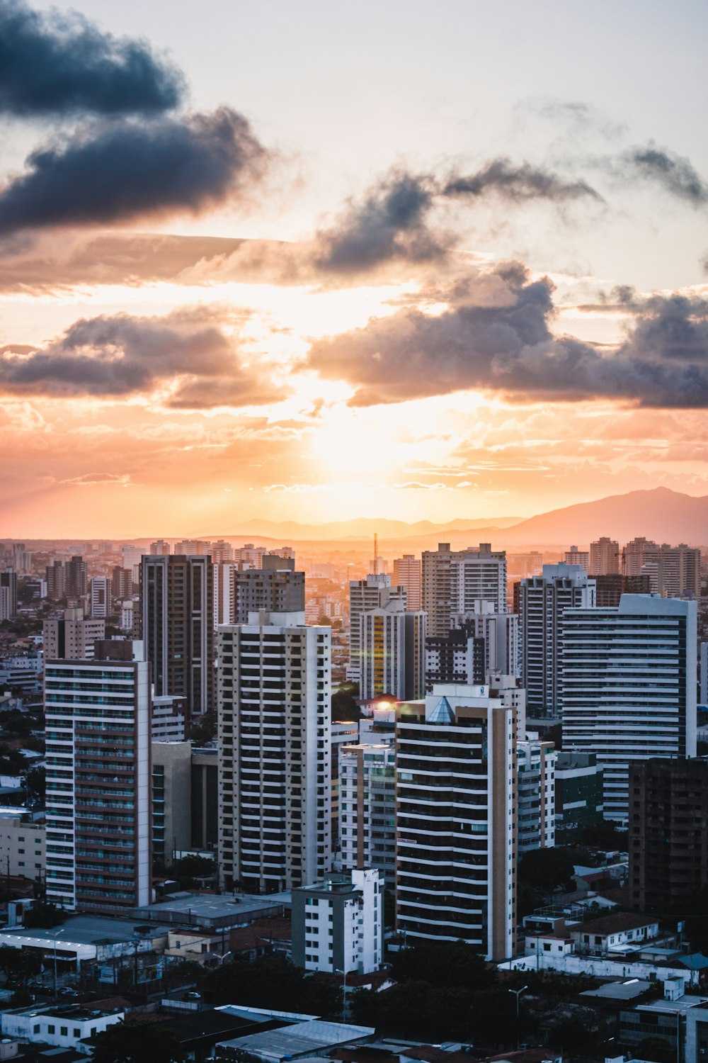 city skyline under orange and gray cloudy sky during sunset