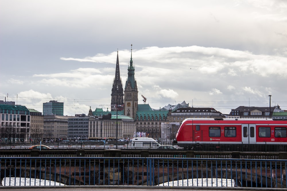 red and white train on rail bridge near city buildings during daytime