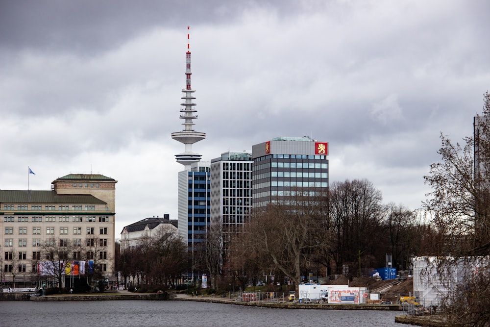 white and red tower near city buildings under white clouds during daytime