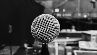 Black and white close-up of a microphone with urban graffiti blurred in the background.