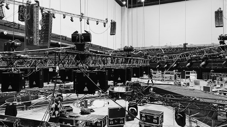 The scene features an intricate network of truss systems, hoists, and lighting equipment suspended a