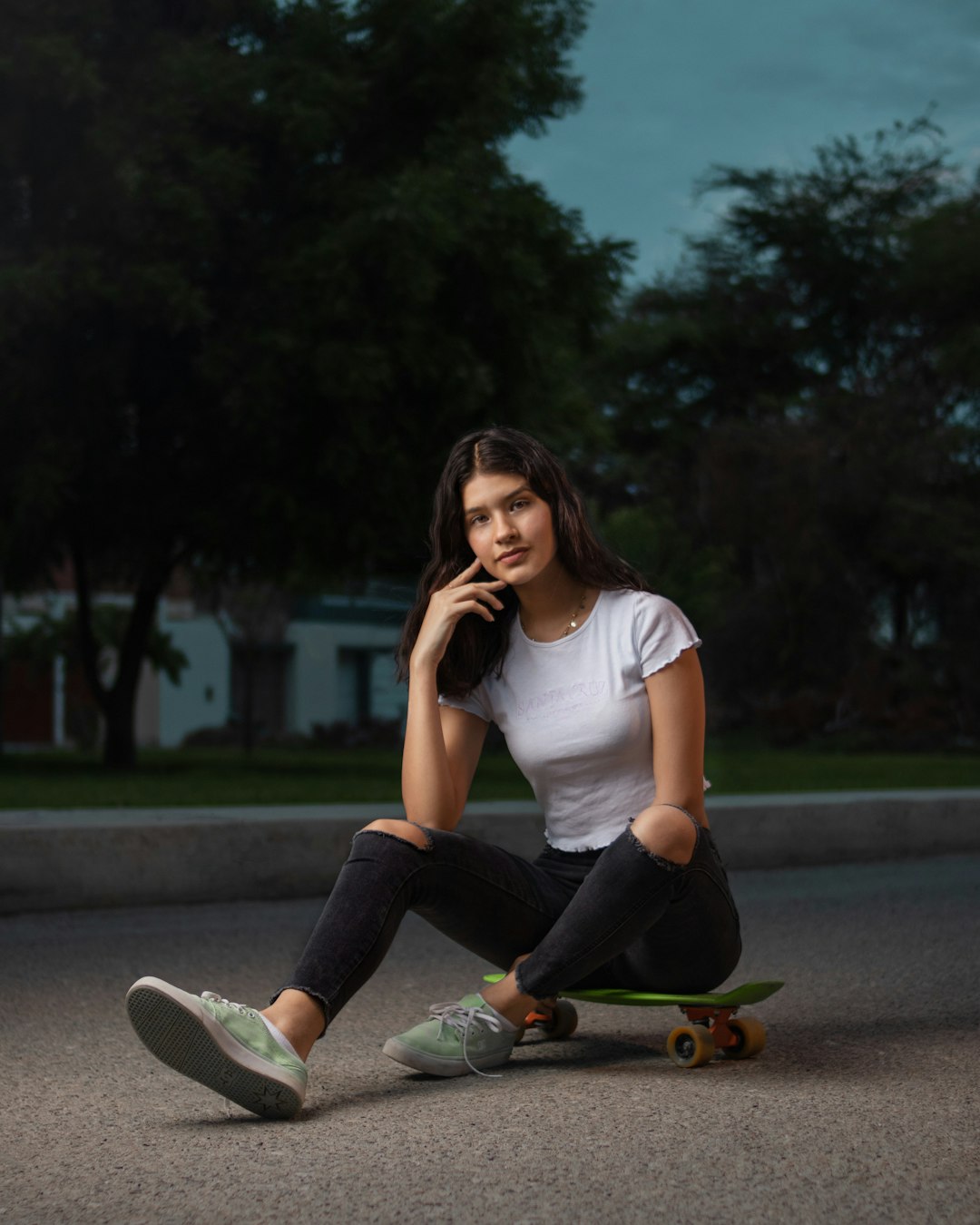 woman in white crew neck t-shirt and black pants sitting on gray concrete road during