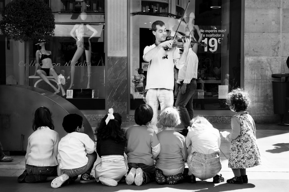 grayscale photo of people in white shirts playing violin
