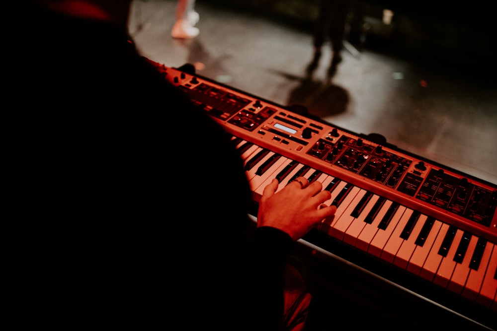 person playing piano on red and black area rug