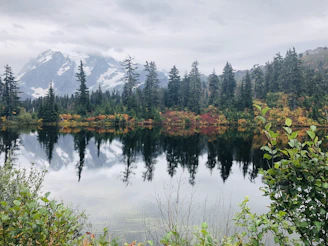 Snow-capped mountains framing the lake with reflections of autumn foliage in the water