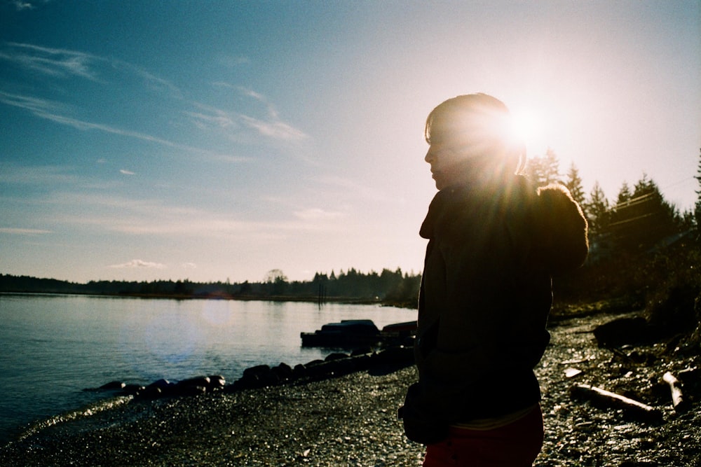 man in black jacket standing near lake during daytime