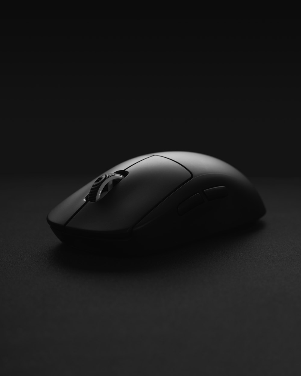 mouse de computador preto sem fio na superfície preta
