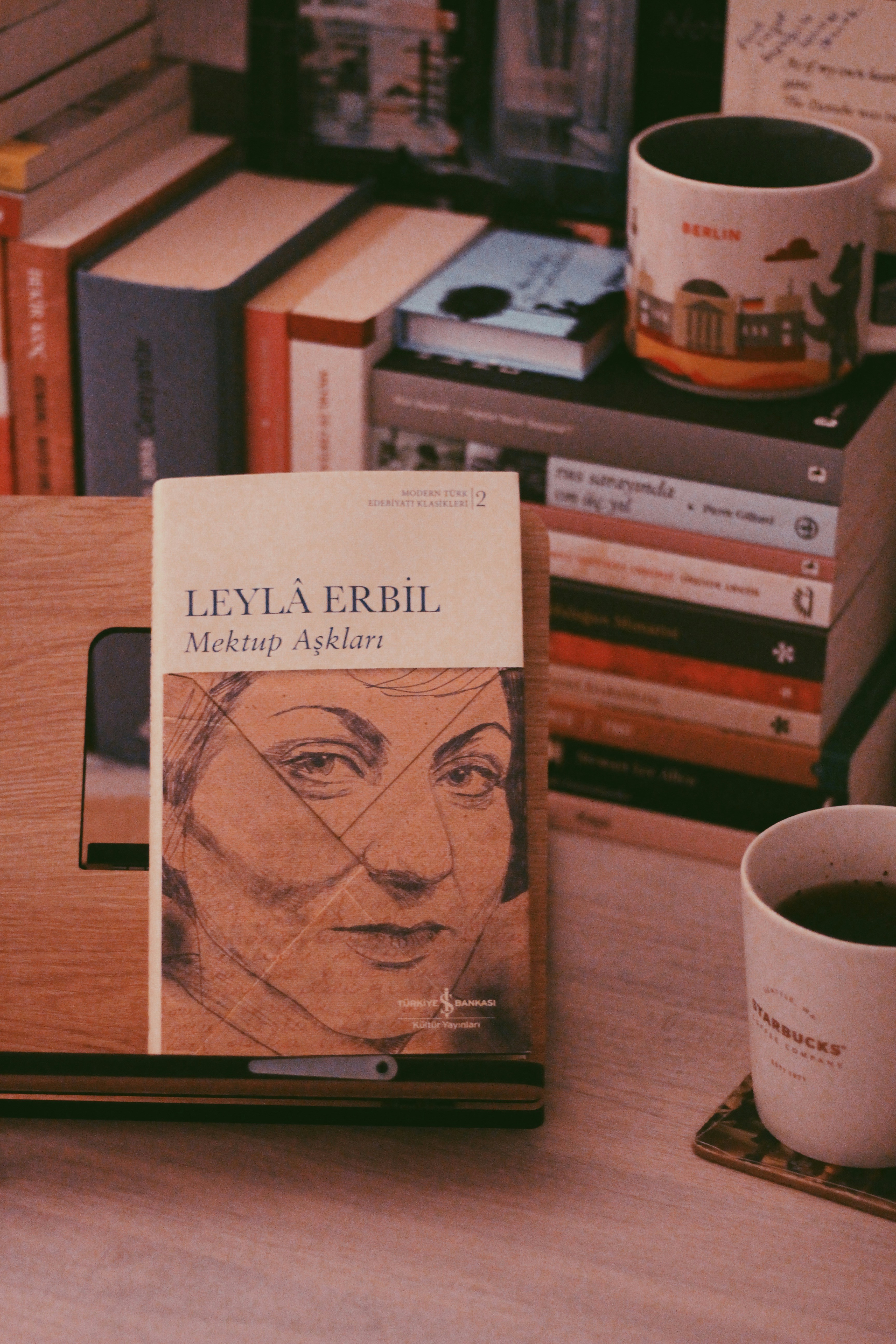An open book on a wooden stand beside a coffee mug.