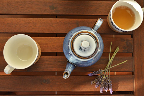 A peaceful scene of a ceramic teapot with a deep blue glaze, surrounded by fresh herbs.