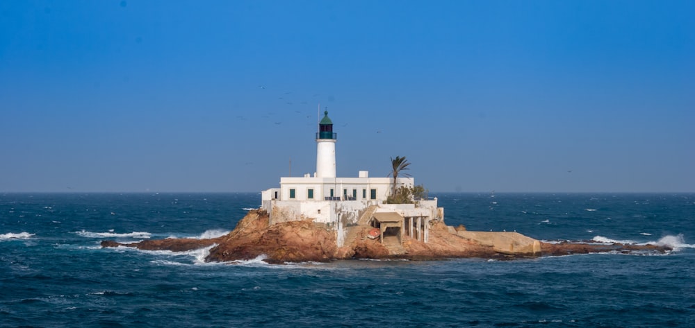 white lighthouse on brown rock formation near body of water during daytime