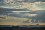 Wide shot of rolling hills with clouds drifting above at sunrise