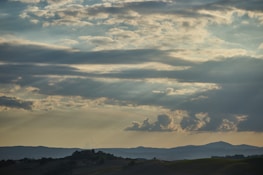 Wide shot of rolling hills with clouds drifting above at sunrise
