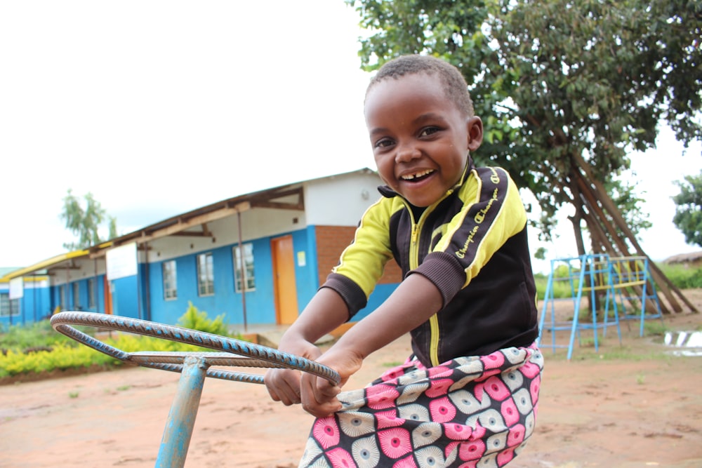 boy in yellow and black polo shirt holding pink and white floral bag