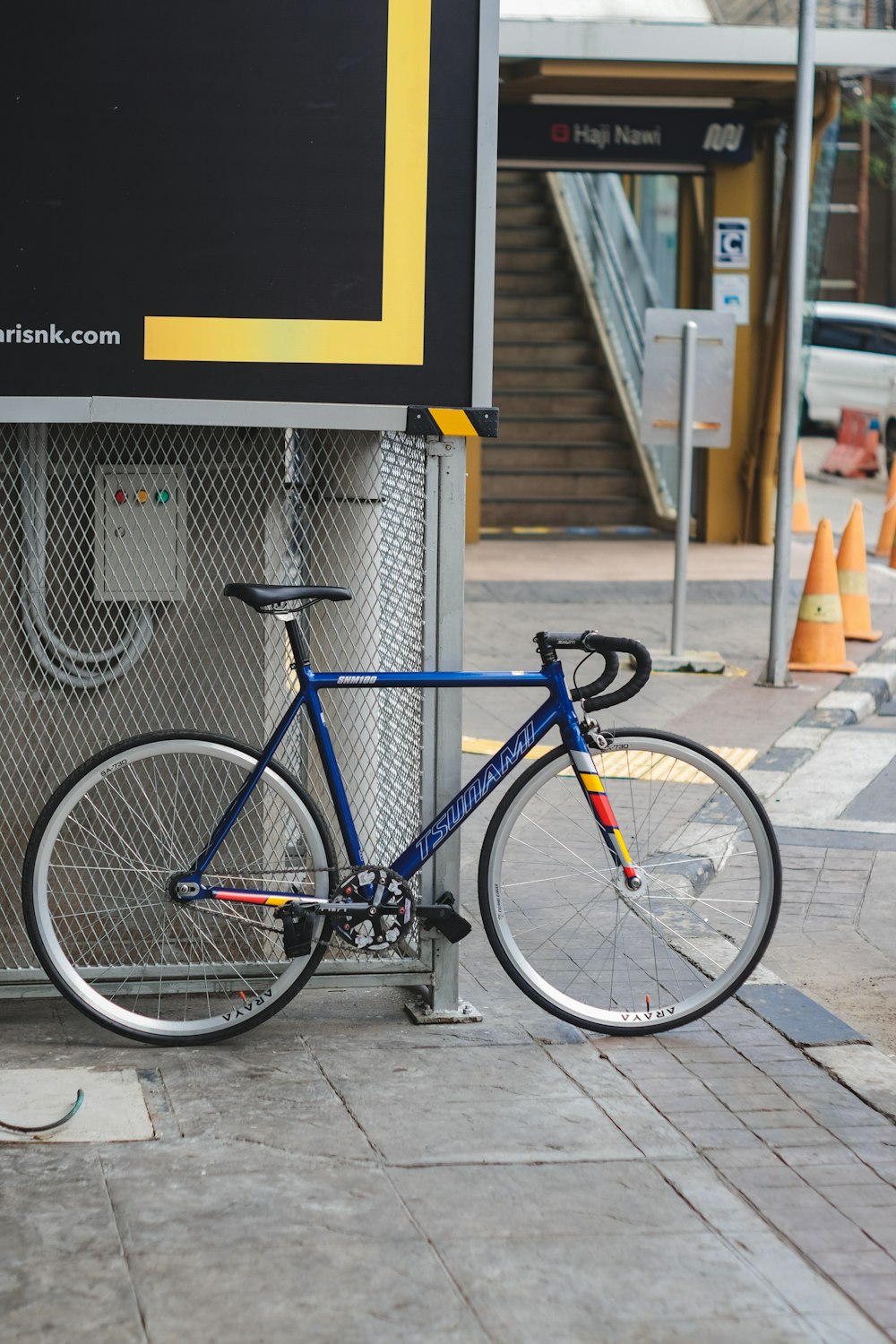 Bici da strada blu e nera parcheggiata accanto a un edificio in cemento bianco durante il giorno