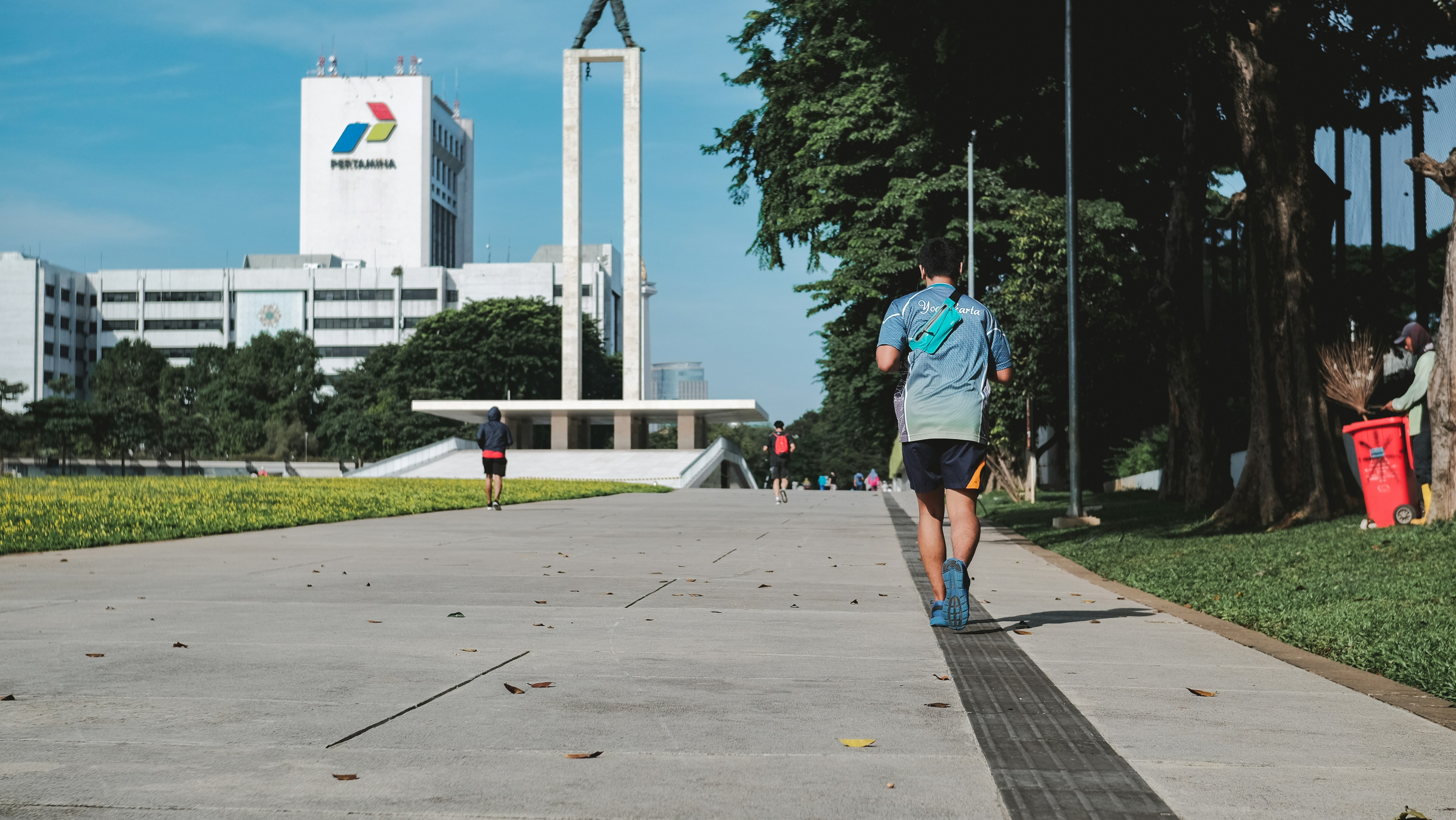 homme en chemise bleue et short bleu marchant sur le trottoir pendant la journée