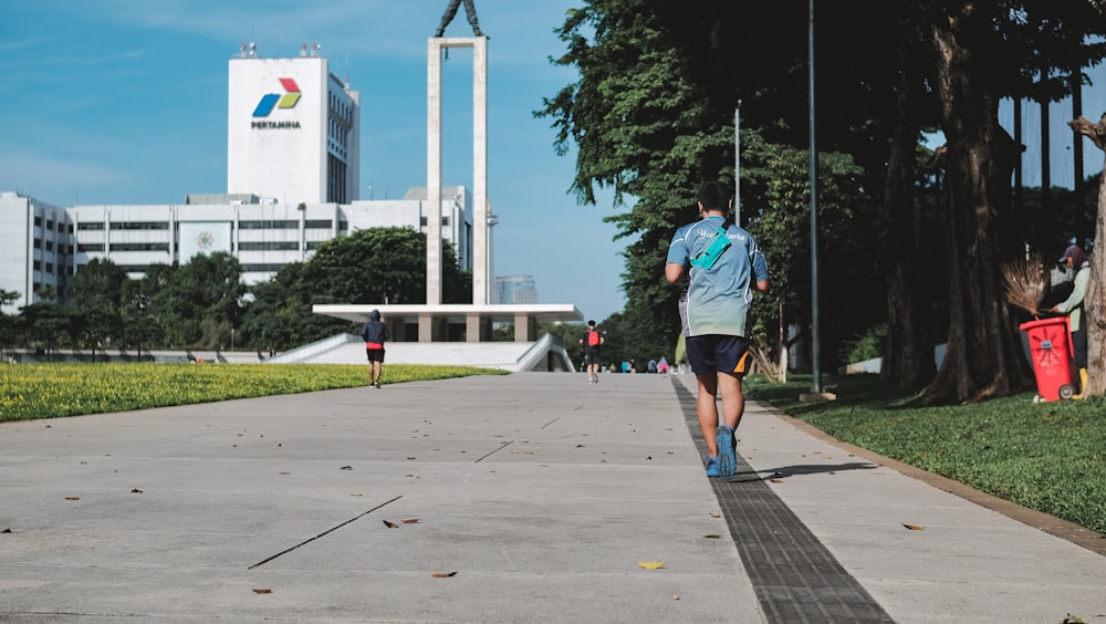 man in blue shirt and blue shorts walking on sidewalk during daytime