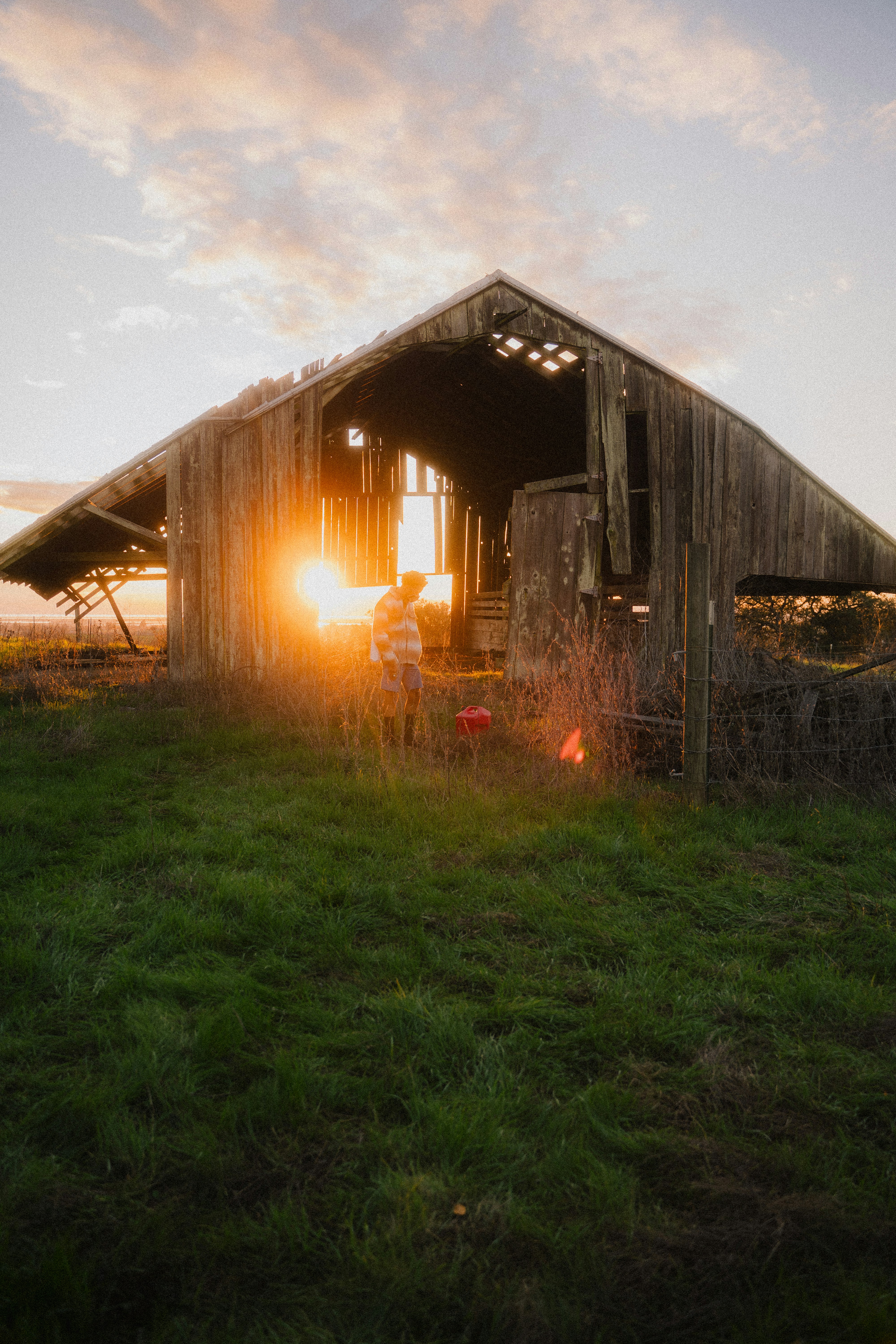 Braunes Holzhaus auf grünem Rasenfeld bei Sonnenuntergang