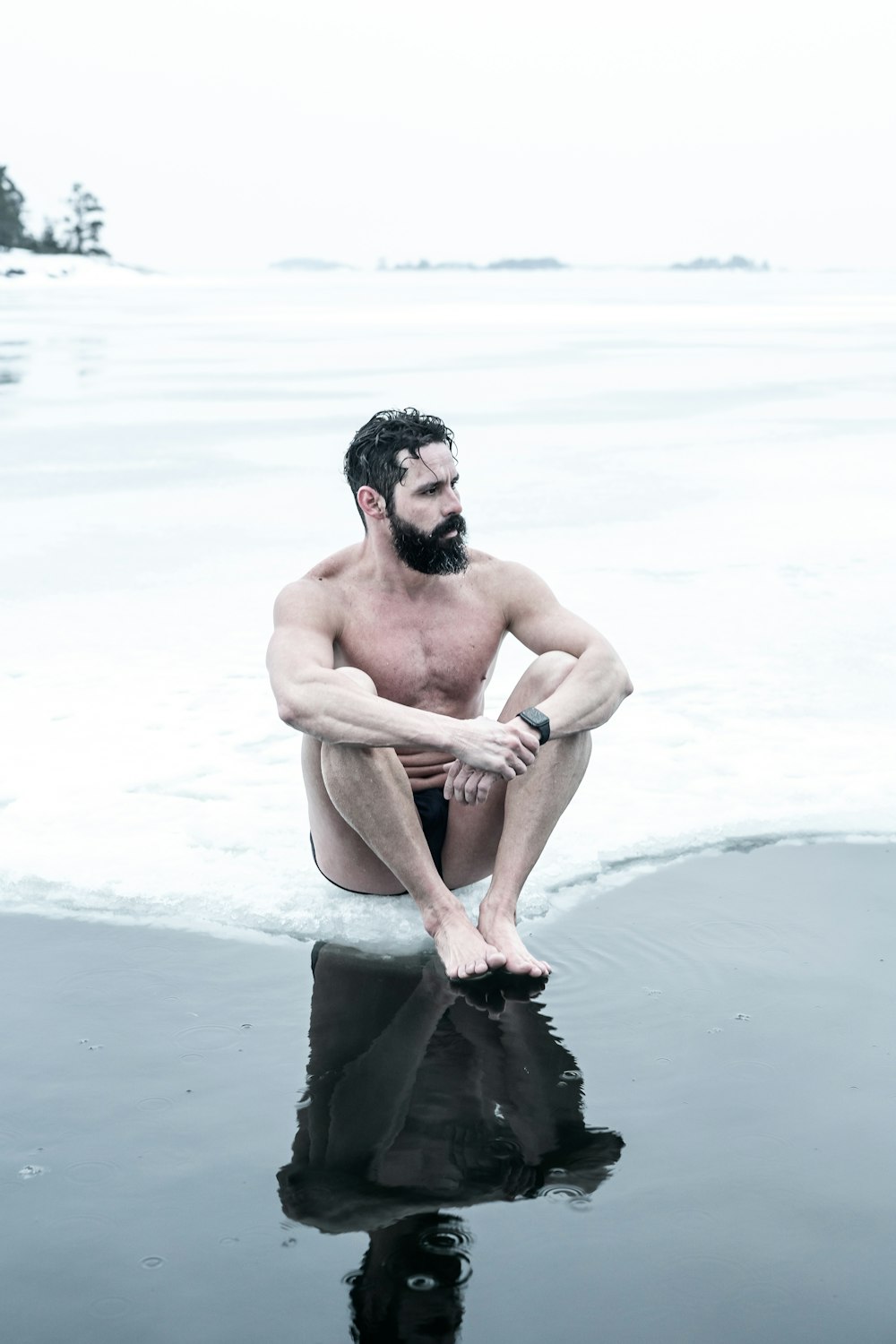 topless man sitting on rock on beach