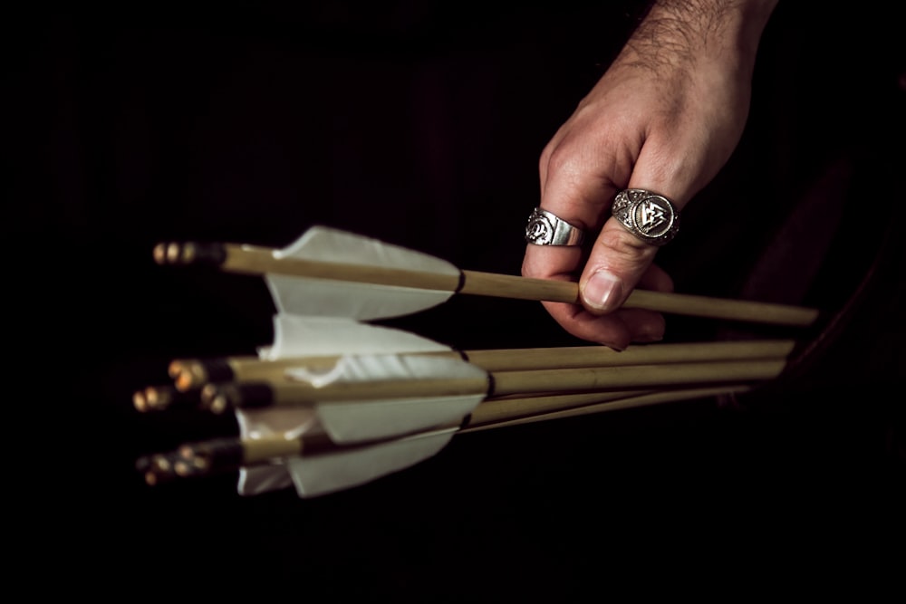 person wearing gold ring holding brown wooden sticks