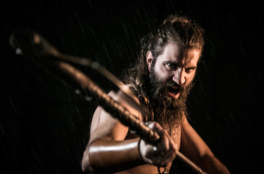 topless man holding black metal bar