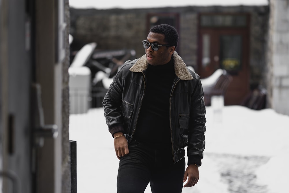 man in black leather jacket and black pants standing on snow covered ground during daytime