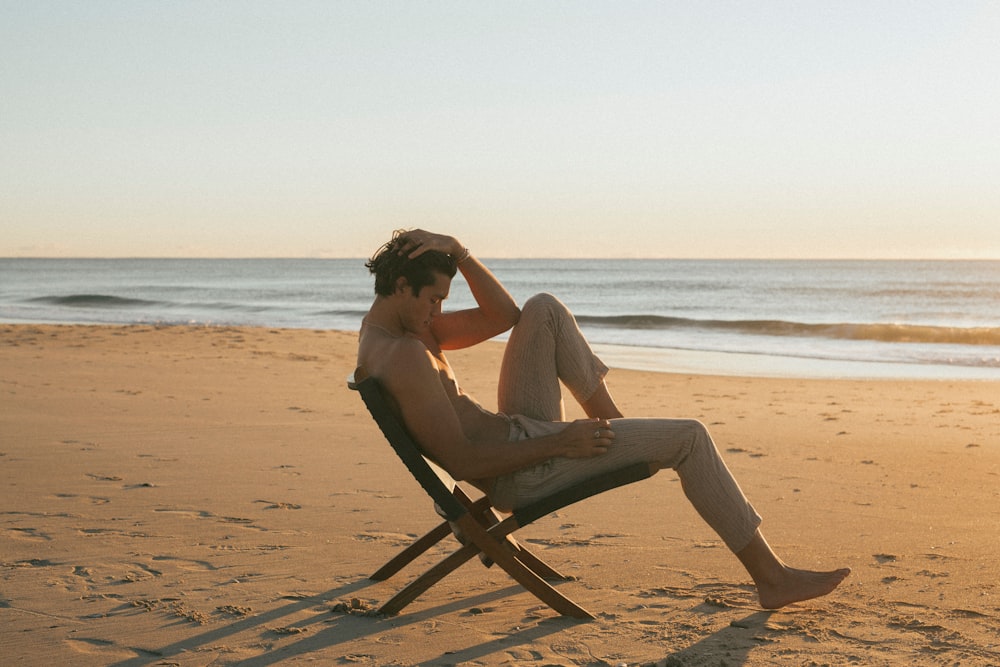 woman in white dress sitting on brown wooden folding chair on beach during daytime