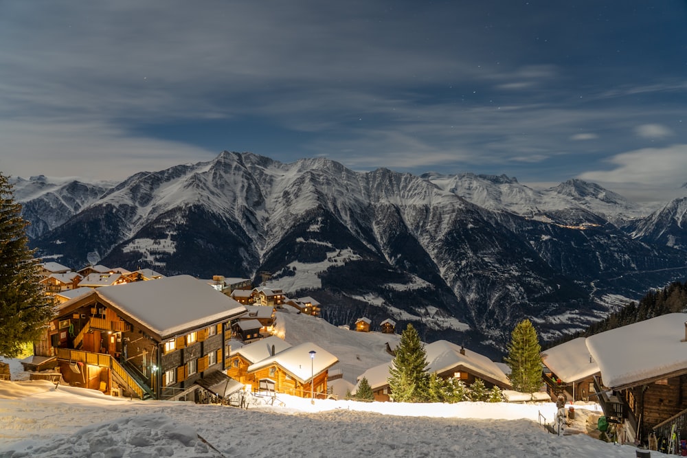 Braunes Holzhaus auf schneebedecktem Boden in der Nähe eines schneebedeckten Berges tagsüber