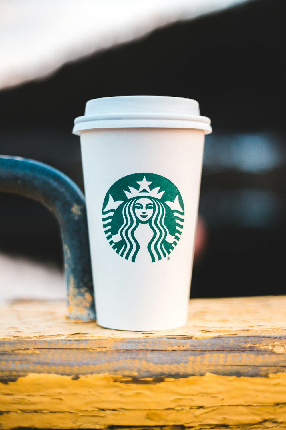 Taza de Starbucks blanca y verde sobre mesa de madera marrón