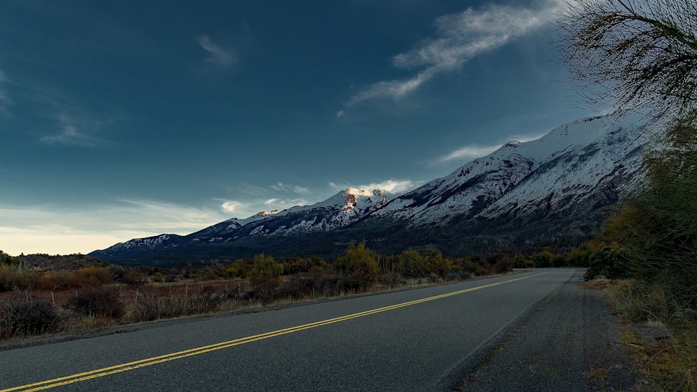 gray concrete road near mountain under blue sky during daytime