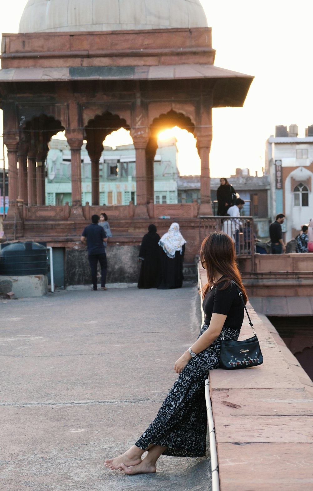Frau in schwarz-weißem Kleid sitzt tagsüber auf einer Betonbank