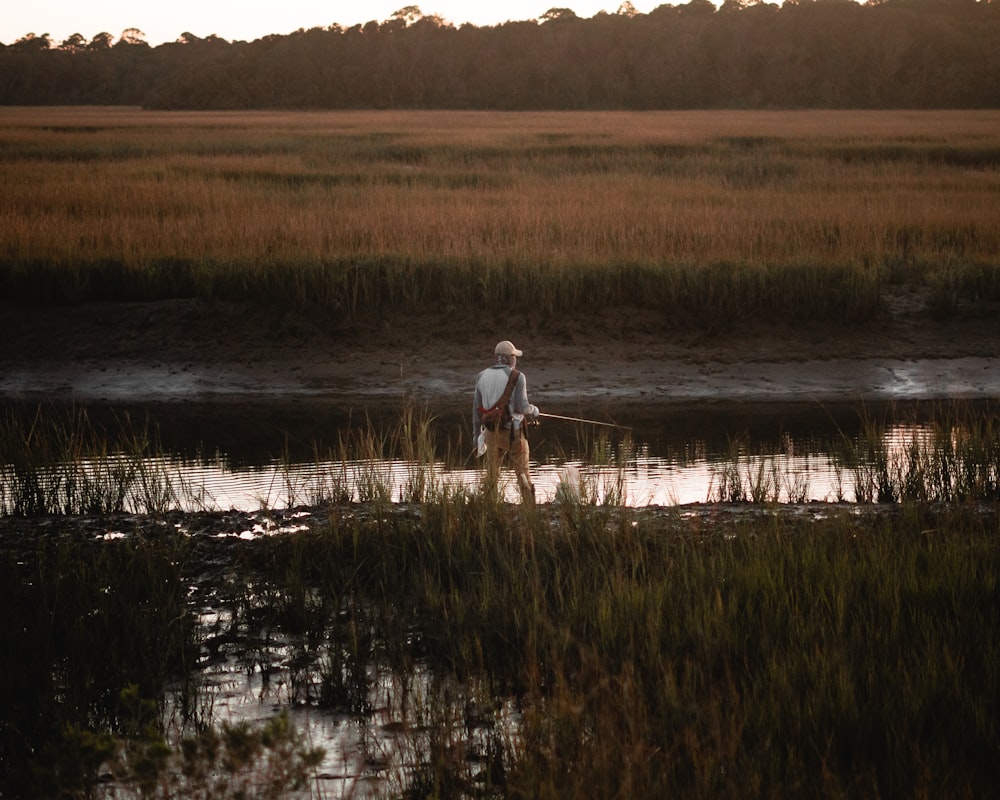 person in white shirt and black pants standing on brown grass field during daytime