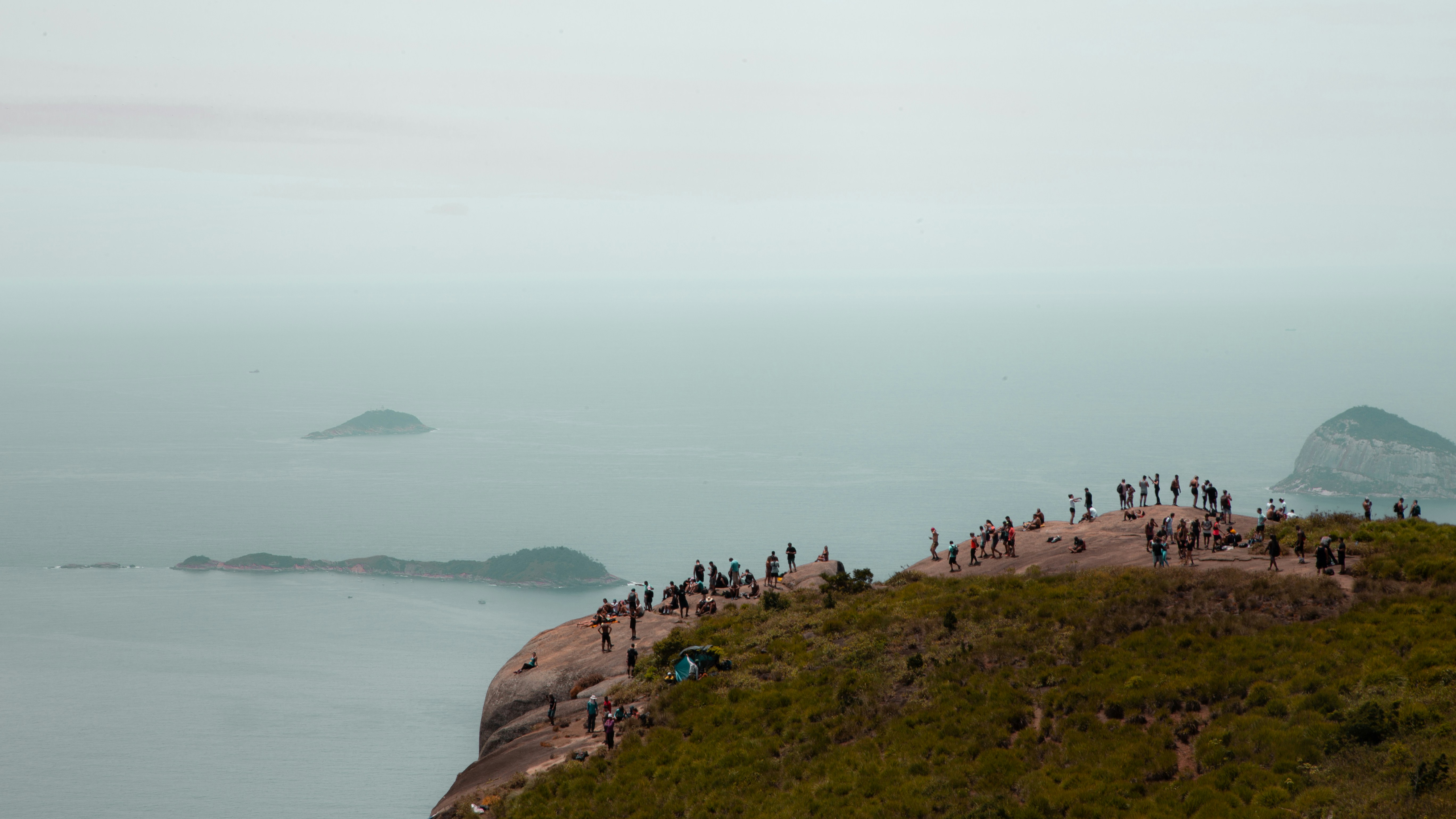 people on brown rock formation near body of water during daytime