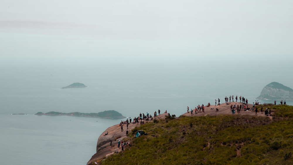Menschen auf braunen Felsformationen in der Nähe von Gewässern während des Tages