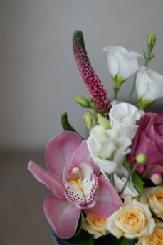 A close-up of a hand-tied bouquet featuring elegant orchids and lush greenery, perfect for gifting