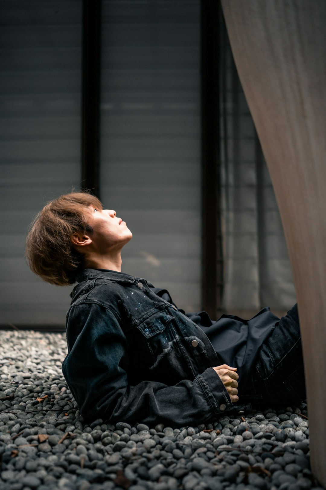 woman in black leather jacket sitting on train rail during daytime