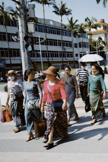 A diverse group of people wearing trendy outfits walking outdoors in natural light.