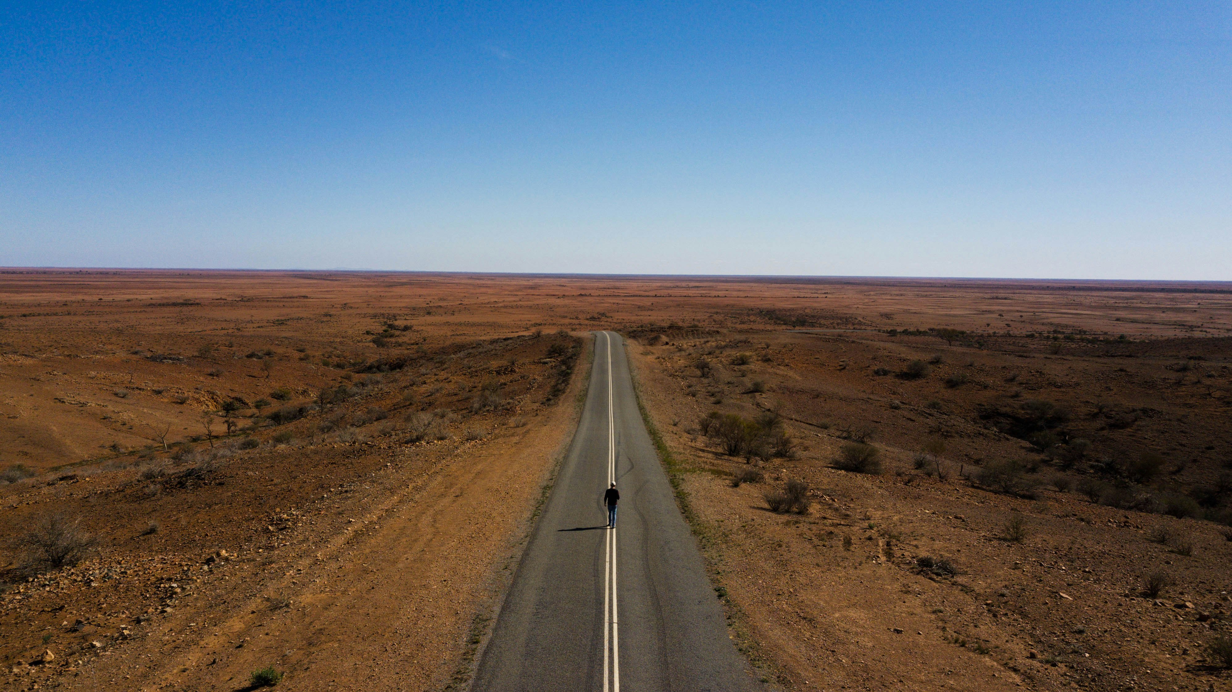 gray concrete road between brown field under blue sky during daytime