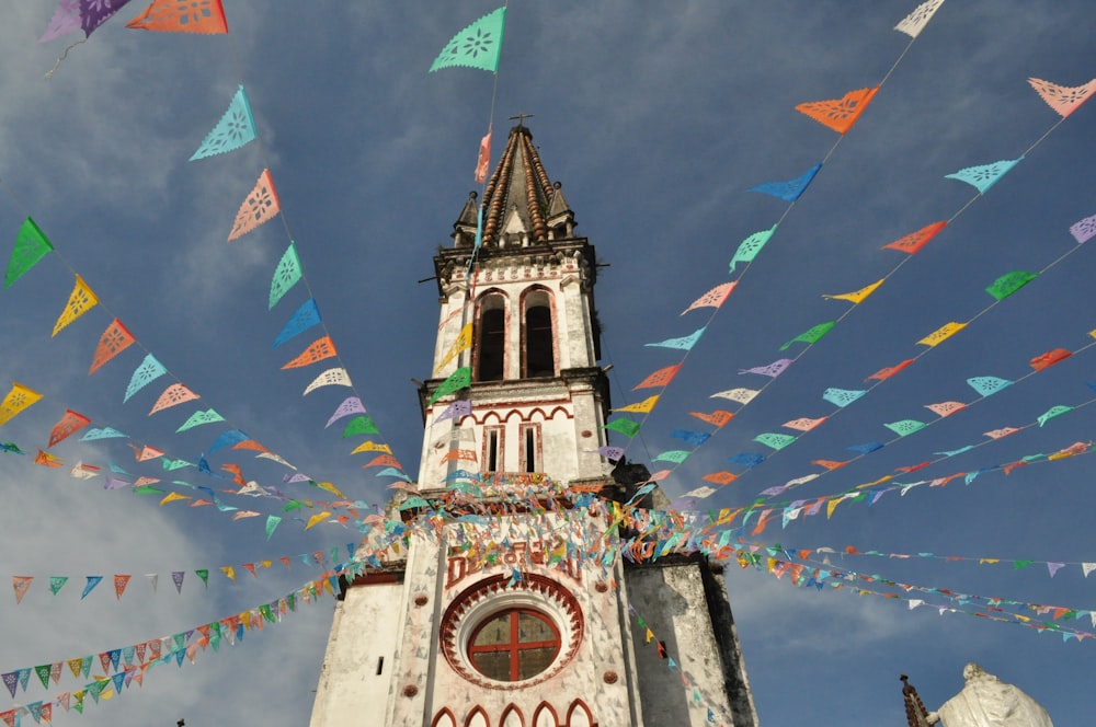 Edificio de hormigón blanco con banderas en la parte superior bajo el cielo azul durante el día