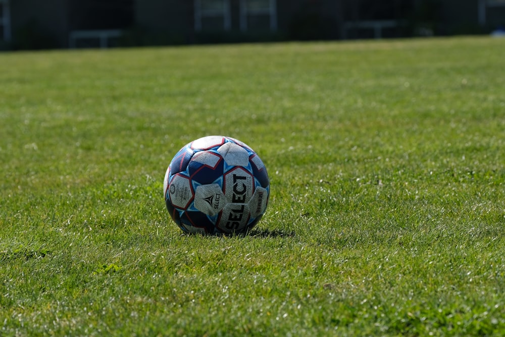 blue white and red soccer ball on green grass field during daytime